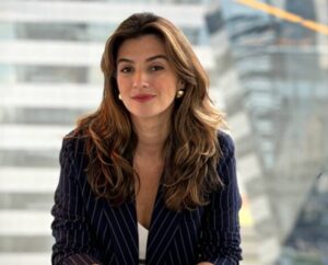 Carolina Riotto é loira, tem cabelos compridos e está de blazer preto