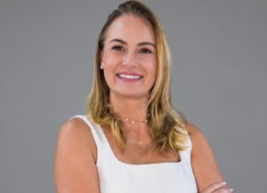 Vivian Monge é loira, cabelo na altura dos ombros, está de camiseta branca e recentemente assumiu a direção-geral da ABAI Brasil