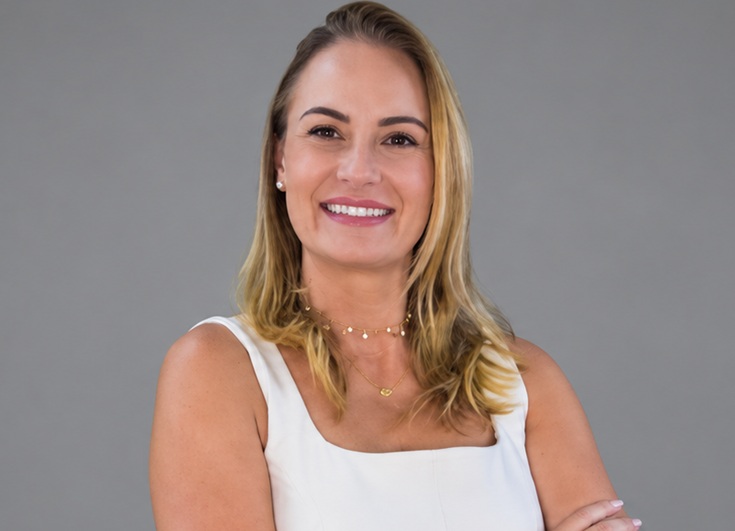 Vivian Monge é loira, cabelo na altura dos ombros, está de camiseta branca e recentemente assumiu a direção-geral da ABAI Brasil
